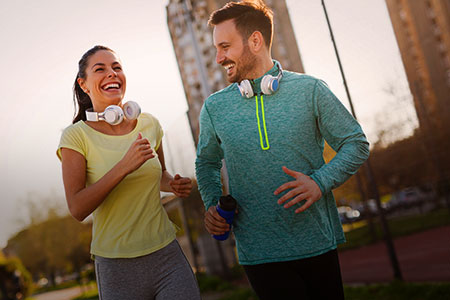 Imagem de duas pessoas uma mulher e um homem sorridentes praticando exercicio fisico